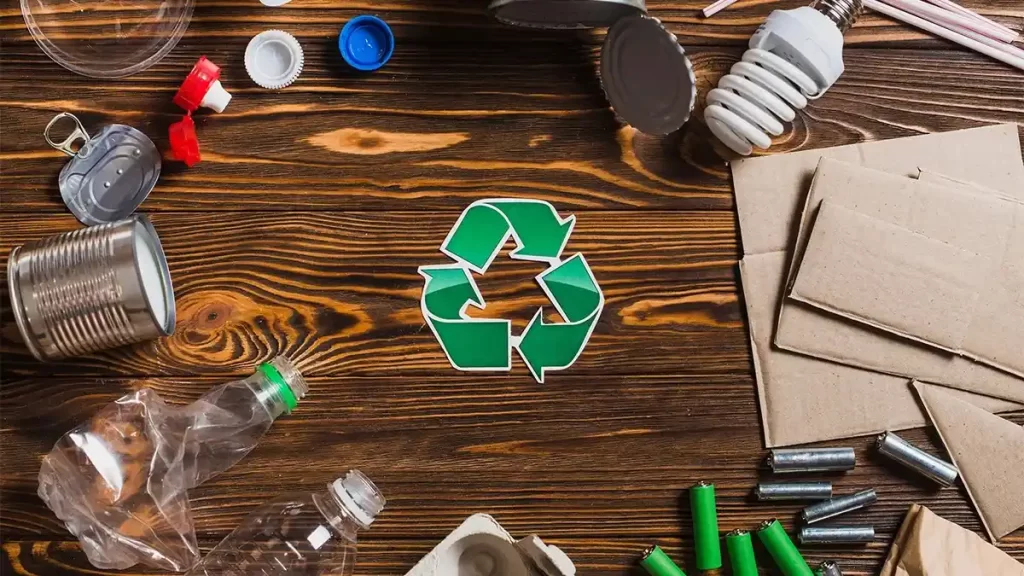 Variety of recyclable materials around a green recycling symbol on a wooden surface - Recycling Scrap: A Step Towards a Sustainable Future.