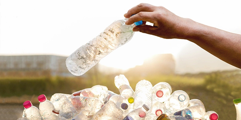 Hand holding plastic bottle over pile of plastic waste - Types of Scrap Materials and Their Recycling Processes, Plastic Recycling.